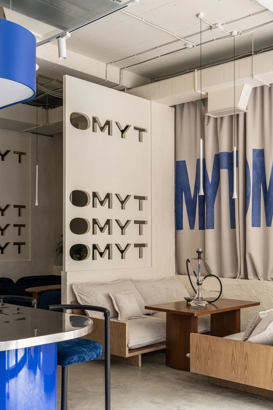 Светлые диваны, деревянный стол и зеркальная перегородка OMYT